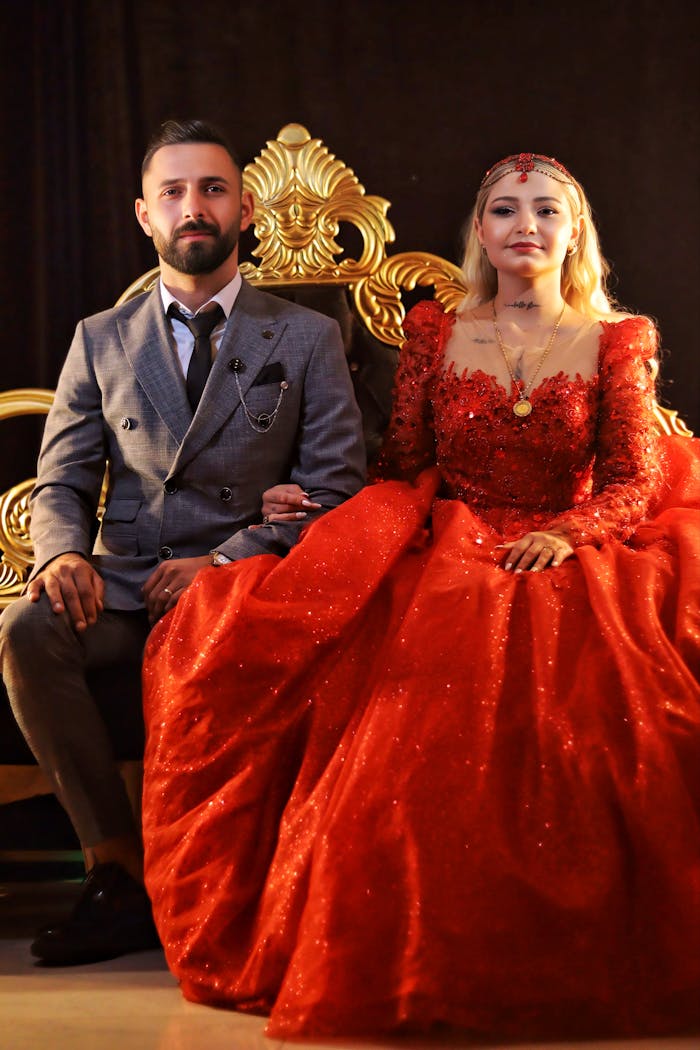 A couple in formal attire seated on a decorative chair, embracing elegance and style.